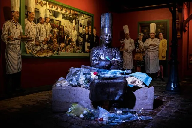 Flowers are pictured next to a statue of French chef Paul Bocuse in the courtyard of his restaurant, “L'auberge du Pont de Collonges”, on January 20, 2018 in Collonges-au-Mont-d'Or, near Lyon. French chef Paul Bocuse died at the age of 91 on January 20, 2018. (Photo by Jeff Pachoud/AFP Photo)
