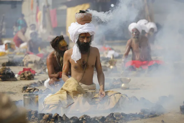 Hindu holy men burn dried cow dung cakes as they perform a ritual at Sangam, confluence of rivers Ganges and Yamuna on “Basant Panchami” day at the annual traditional fair of Magh Mela in Allahabad, India, Monday, January 22, 2018. Basant Panchami is celebrated by worshipping Hindu goddess of knowledge and wisdom, Saraswati and marks the advent of spring. Hundreds of thousands of devout Hindus bathe at the confluence during the astronomically auspicious period of over 45 days celebrated as “Magh Mela”. (Photo by Rajesh Kumar Singh/AP Photo)
