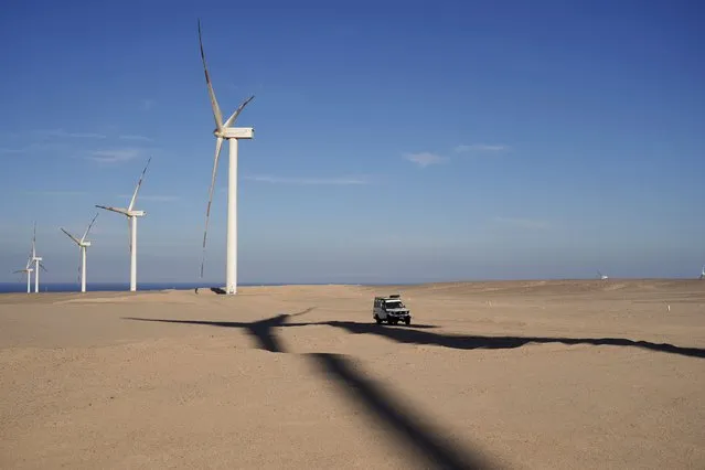 A vehicle drives near wind turbines at Lekela wind power station, near the Red Sea city of Ras Ghareb, some 300 km (186 miles), from Cairo, Egypt, October 12, 2022. The U.N. climate summit is back in Africa after six years and four consecutive Europe-based conferences. The conference – known as COP27 – will be held in the resort city of Sharm el-Sheikh in Egypt. (Photo by Amr Nabil/AP Photo)