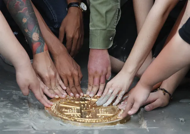 Pro-democracy student leaders install a plaque declaring “This country belongs to the people” at the Sanam Luang field during a protest in Bangkok, Thailand, Sunday, Septemner 20, 2020. Thousands of demonstrators turned out Saturday for a rally to support the student-led protest movement's demands for new elections and reform of the monarchy. (Photo by Sakchai Lalit/AP Photo)