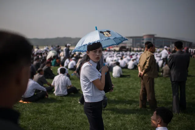 A woman holding an umbrella waits for the start of the first Wonsan Friendship Air Festival in Wonsan on September 24, 2016. (Photo by Ed Jones/AFP Photo)