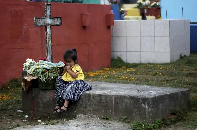 A child sits on a grave in the cemetery of Tactic, in the Alta Verapaz region, in Guatemala, November 1, 2015. People visit cemeteries and graves of deceased relatives and friends to commemorate All Saints Day, which falls on November 1. (Photo by Josue Decavele/Reuters)