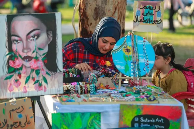 An artist paints a girl's face during the Baghdad International Festival of Flowers and Gardens organized to mark Nowruz celebrations symbolizing the beginning of spring, at the al-Zawraa Zoo in Baghdad on March 16, 2023. (Photo by Ahmad Al-Rubaye/AFP Photo)