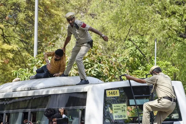 A policeman drags a supporter of opposition Congress party atop a police vehicle as they are detained while protesting against their leader Rahul Gandhi's expulsion from Parliament in New Delhi, India, Monday, March 27, 2023. (Photo by Deepanshu Aggarwal/AP Photo)