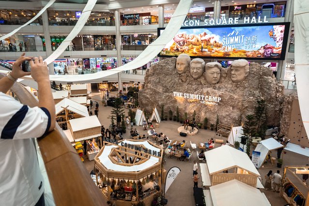A visitor takes a photo of a parody Mount Rushmore sculpture depicting the faces of Russia's President Vladimir Putin (L), China's President Xi Jinping (2nd L), North Korea's leader Kim Jong-un (2nd R), and US President Donald Trump (R) at “The Summit Camp” camping and outdoors experience at a shopping mall in Bangkok on September 24, 2025. (Photo by Chanakarn Laosarakham/AFP Photo)