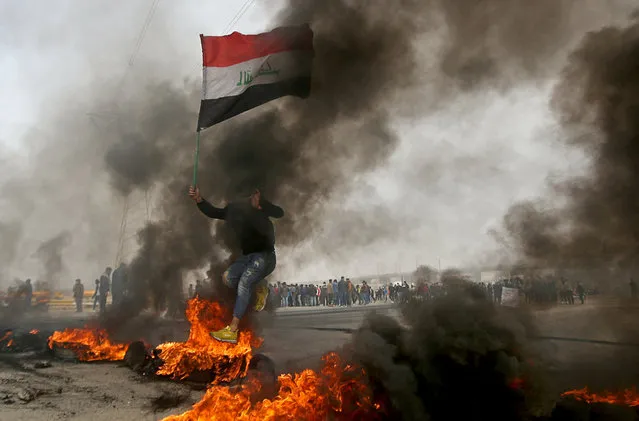 An Iraqi demonstrator jumps over a burning tire during anti-government protests in Basra, Iraq, December 20, 2020. (Photo by Essam al-Sudani/Reuters)