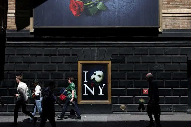 People walk by a poster of The Phantom of the Opera displayed on the Majestic Theatre ahead of its final performance on April 16 after 35 years on Broadway in New York City, U.S., April 12, 2023. (Photo by Andrew Kelly/Reuters)