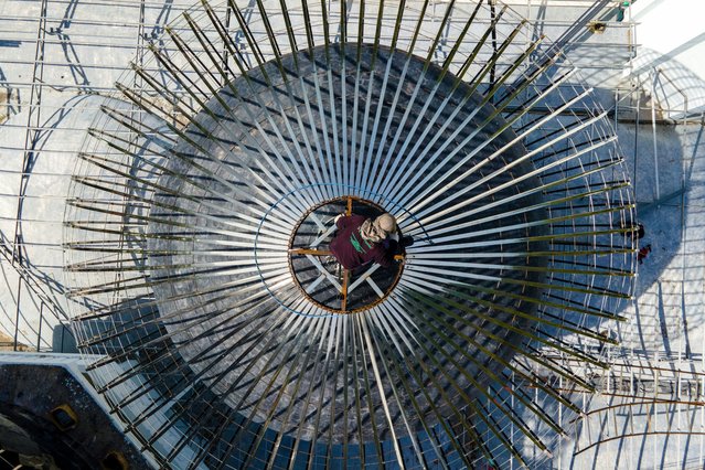 This photo shows an aerial view of a worker taking part in the reconstruction of a dome of the Rahmatullah Mosque, a landmark building that withstood the devastation of the 2004 tsunami, in Lhoknga, Aceh province on September 10, 2025. (Photo by Chaideer Mahyuddin/AFP Photo)