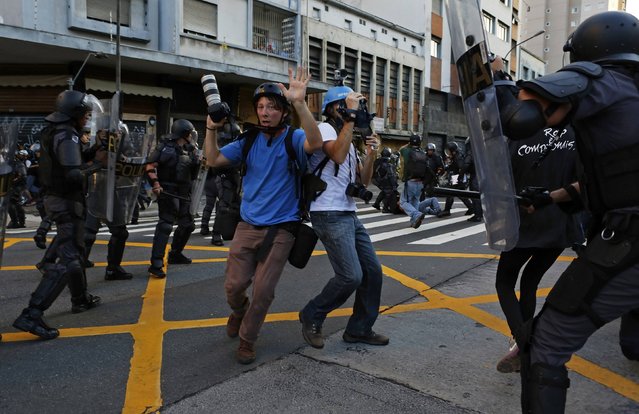 Photographers raise their hands, surrounded by riot police, during a protest against fare hikes for city buses, subway and trains in Sao Paulo January 9, 2015. The large street protest against rising bus fares in Sao Paulo, Brazil's biggest city, ended in tear gas and 32 arrests on Friday, echoing the disruptions that led up to last year's soccer World Cup. (Photo by Nacho Doce/Reuters)
