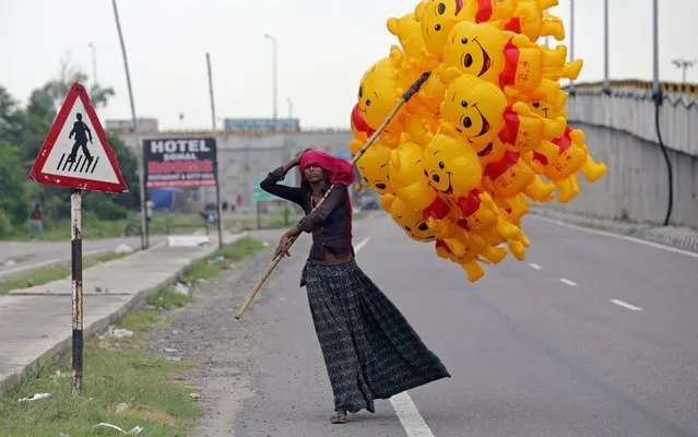 A vendor adjusts her scarf as she sells Winnie the Pooh cartoon-shaped balloons on a highway during the weekend lockdown in Amritsar, India, 30 August 2020. Another lockdown was imposed by the state government to control the spread of novel coronavirus which causes the Covid19 disease. (Photo by Raminder Pal Singh/EPA/EFE/Rex Features/Shutterstock)