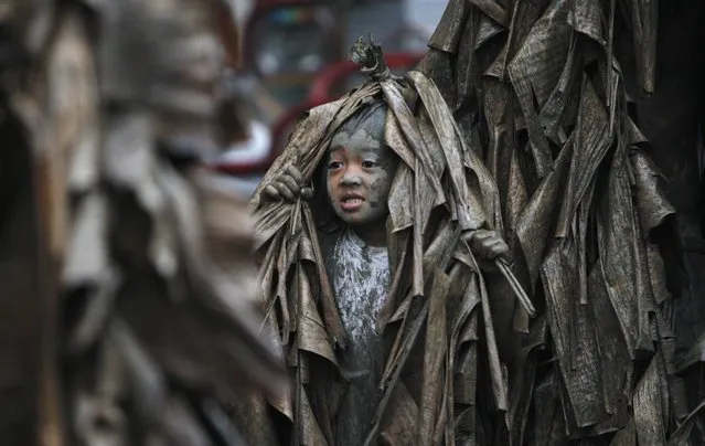 A boy, covered with mud and dried banana leaves, walks around the village to ask for candles before attending a mass celebrating the feast day of the Catholic patron Saint John the Baptist in the village of Bibiclat, Nueva Ecija, north of Manila, June 24, 2013. Hundreds of devotees took part in this annual religious tradition, which has been held in the village since 1945. (Photo by Cheryl Ravelo/Reuters)
