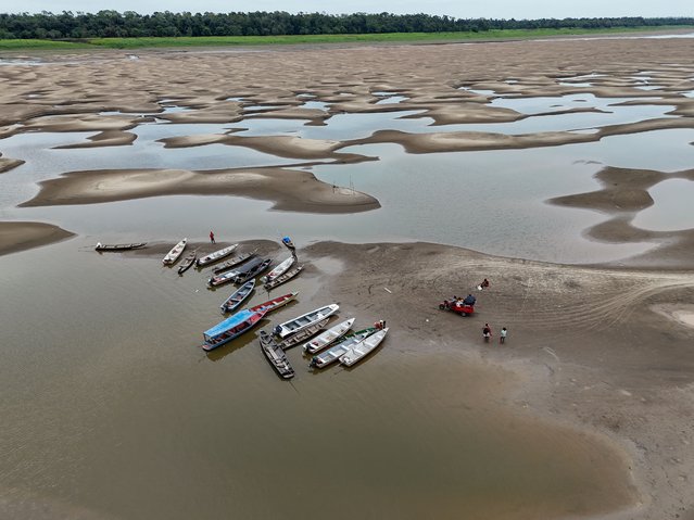 Aerial view of river dwellers using a tricycle to transport food and passengers along the dry bed of the Solimoes River, near the Monte Sinai Community, in Manacapuru, Amazonas state, northern Brazil, on September 30, 2024. Several tributaries of the Amazon River, one of the longest and most abundant in the world, are in a “critical situation of water scarcity” due to the historic drought affecting Brazil, authorities reported on September 30. (Photo by Michael Dantas/AFP Photo)