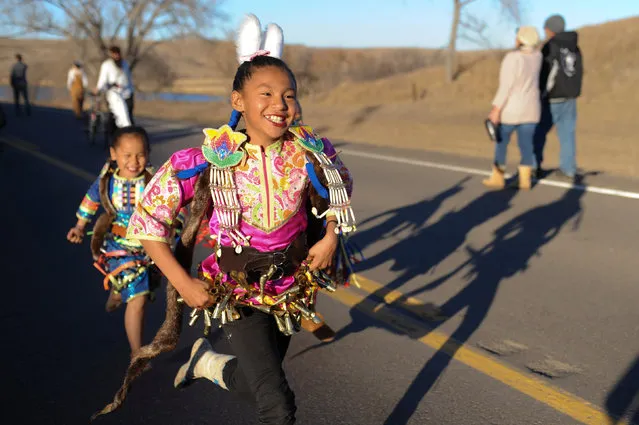 PJ Herrera, 10, runs along a road while wearing ceremonial garb during a protest against the Dakota Access pipeline near the Standing Rock Indian Reservation near Cannon Ball, North Dakota, U.S. November 12, 2016. (Photo by Stephanie Keith/Reuters)