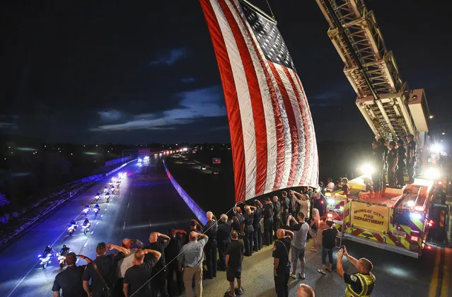 Utah firefighter Matt Burchett, 42, who died fighting a wildfire in California, is honored by a detail along Murray Parkway as his body is returned home, traveling along Interstate 215 after being flown to the Utah Air National Guard in Salt Lake City, Wednesday, August 15, 2018.  Burchett was hit by a falling tree and died Monday night while fighting the largest blaze in California history, the Mendocino Complex fire north of San Francisco. (Photo by Francisco Kjolseth/The Salt Lake Tribune via AP Photo)