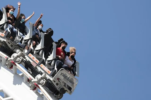 People ride a roller coaster at Six Flags Magic Mountain amusement park on the first day of opening, as the coronavirus disease (COVID-19) continues, in Valencia, California, U.S., April 1, 2021. (Photo by Lucy Nicholson/Reuters)