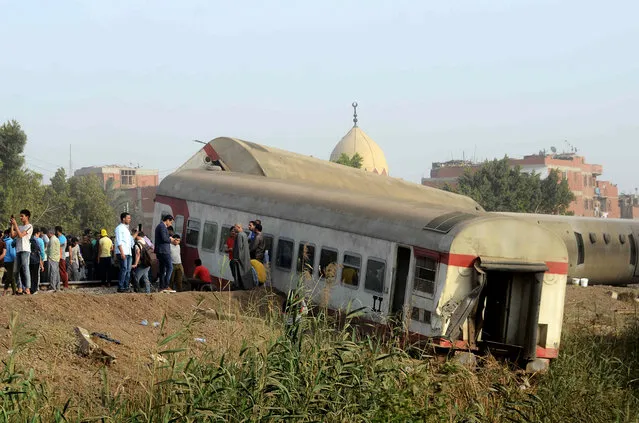 People gather at the site where a passenger train derailed injuring at least 100 people, near Banha, Qalyubia province, Egypt, Sunday, April 18, 2021. (Photo by Tarek Wagih/AP Photo)