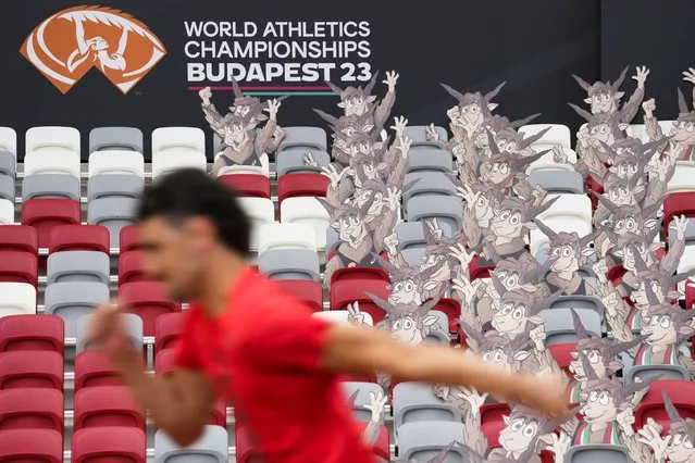 An athlete runs past cutouts of the games' mascot, Youhuu, a native Hungarian sheep, at the National Athletics Centre, one day ahead of the start of the World Athletics Championships in Budapest, Hungary, Friday, August 18, 2023. (Photo by Ashley Landis/AP Photo)