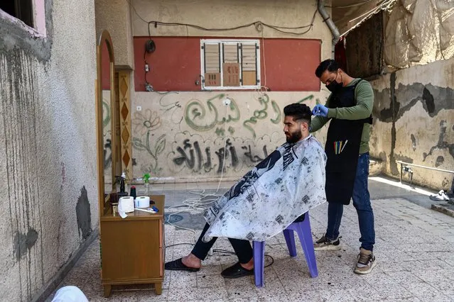 Palestinian barber Mohammed al-Bouji, 37, wears a mask and gloves, shaves for clients, in the southern Gaza Strip city of Rafah, on April 28, 2021. Al-Bouji launched The delivery shaving services amid the coronavirus disease (COVID-19). (Photo by APA Images/Rex Features/Shutterstock)