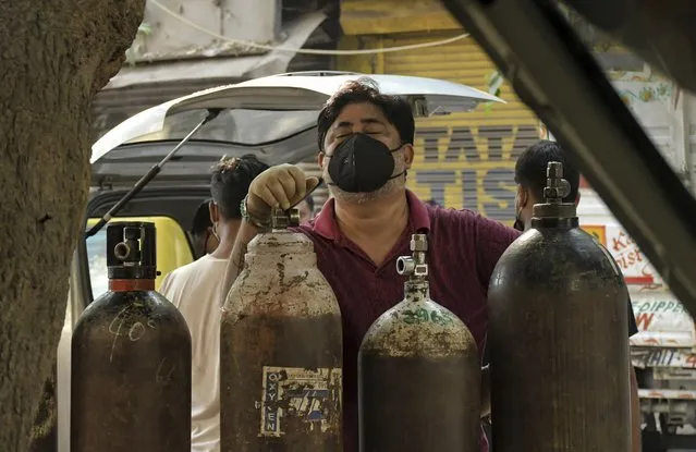 Family member of a COVID-19 patient reacts as he waits to refill an oxygen cylinder at a gas supplier facility in New Delhi, India, Saturday, May 8, 2021. Infections have swelled in India since February in a disastrous turn blamed on more contagious variants as well as government decisions to allow massive crowds to gather for religious festivals and political rallies. (Photo by Ishant Chauhan/AP Photo)