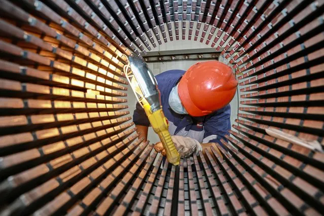 A worker checks a rotor core used for wind turbines at a factory in Nantong, in China's eastern Jiangsu province on September 20, 2023. (Photo by AFP Photo/China Stringer Network)