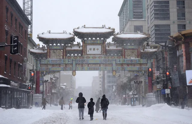 People walk in the snow toward Chinatown's Friendship Archway, Saturday, January 23, 2016, in Washington. (Photo by Nick Wass/AP Photo)