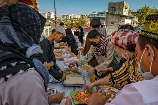 Filipino Muslims eat a meal together as they celebrate Eid al-Fitr at the Garden Mosque on May 13, 2021 in Taguig, Metro Manila, Philippines. Eid al-Fitr marks the end of Ramadan, during which Muslims in countries around the world spend time with family, offer gifts and often give to charity. Parts of the Philippines remain under strict lockdown to curb the spread of the coronavirus, with religious venues restricted to 20 percent capacity only. (Photo by Ezra Acayan/Getty Images)