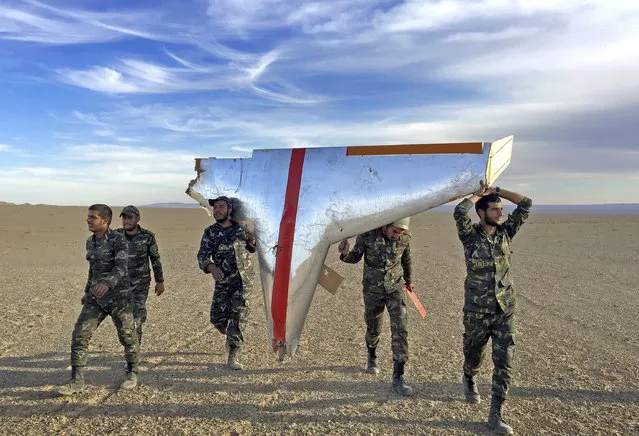 In this photo provided by the Iranian Army Monday, November 5, 2018, soldiers carry the wreckage of a drone during drills in Semnan, Iran. Iran greeted the re-imposition of U.S. sanctions on Monday with air defense drills and a statement from President Hassan Rouhani that the nation faces a “war situation”, raising Mideast tensions as America's maximalist approach to the Islamic Republic takes hold. (Photo by Iranian Army via AP Photo)
