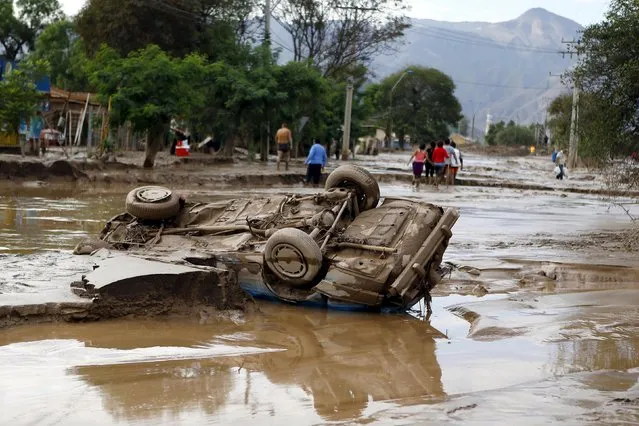 A damaged car covered in mud lies on a street at Copiapo city, March 26, 2015. (Photo by Ivan Alvarado/Reuters)