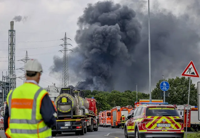 Emergency vehicles of the fire brigade, rescue services and police stand not far from an access road to the Chempark over which a dark cloud of smoke is rising in Leverkusen, Germany, Tuesday, July 27, 2021. After an explosion, fire brigade, rescue services and police are currently in large-scale operation, the police explained. (Photo by Oliver Berg/dpa via AP Photo)