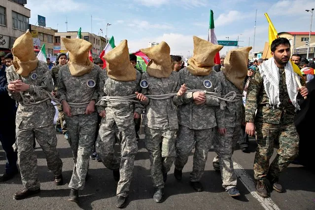 Members of Iranian Basij paramilitary force reenact the January capture of U.S sailors by the Revolutionary Guard in the Persian Gulf, in a rally commemorating the 37th anniversary of Islamic Revolution in Tehran, Iran, Thursday, February 11, 2016. The nationwide rallies commemorate Feb. 11, 1979, when followers of Ayatollah Khomeini ousted U.S.-backed Shah Mohammad Reza Pahlavi. (Photo by Ebrahim Noroozi/AP Photo)