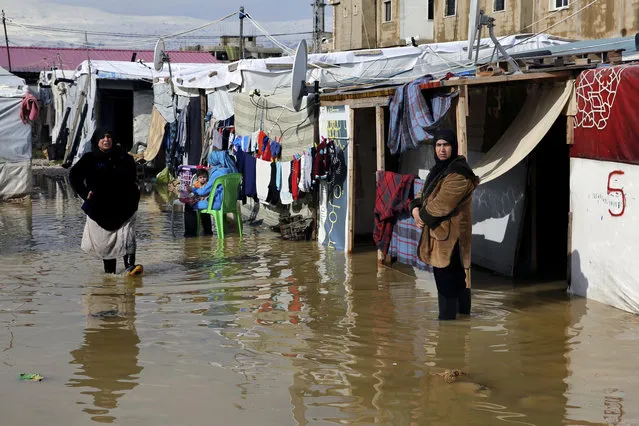 Syrian refugees stand in a pool of mud and rain water at a refugee camp, in the town of Bar Elias, in the Bekaa Valley, Lebanon, Thursday, January 10, 2019. A storm that battered Lebanon for five days displaced many Syrian refugees after their tents got flooded with water or destroyed by snow. (Photo by Bilal Hussein/AP Photo)