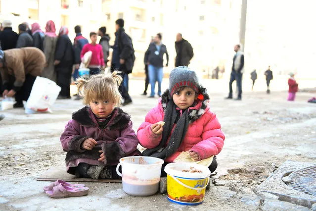 Girls eat a cooked meal provided by the UN through a partner NGO in the east Aleppo neighborhood of Tariq al-Bab, Syria, in this handout picture provided by UNHCR on January 4, 2017. (Photo by Bassam Diab/Reuters)