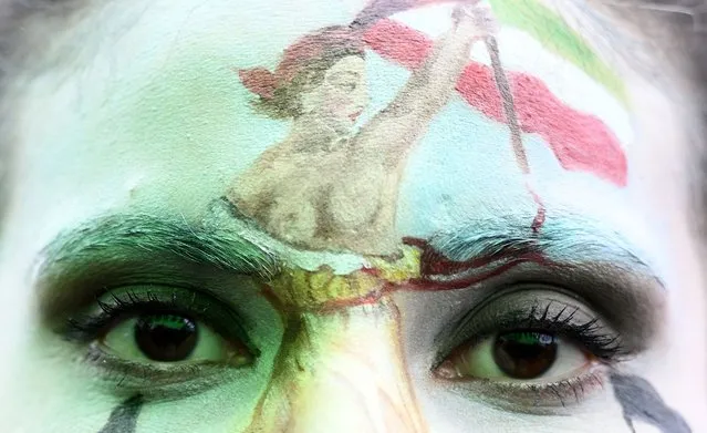A protester wearing face-paint depicting France's iconic “Marianne” leading an uprising, attends a demonstration in support of Kurdish woman Mahsa Amini during a protest on October 2, 2022 on Place de la Republique in Paris, following her death in Iran. Amini died in custody on September 16, 2022, three days after her arrest by the notorious morality police in Tehran for allegedly breaching the Islamic republic's strict dress code for women. (Photo by Stefano Rellandini/AFP Photo)