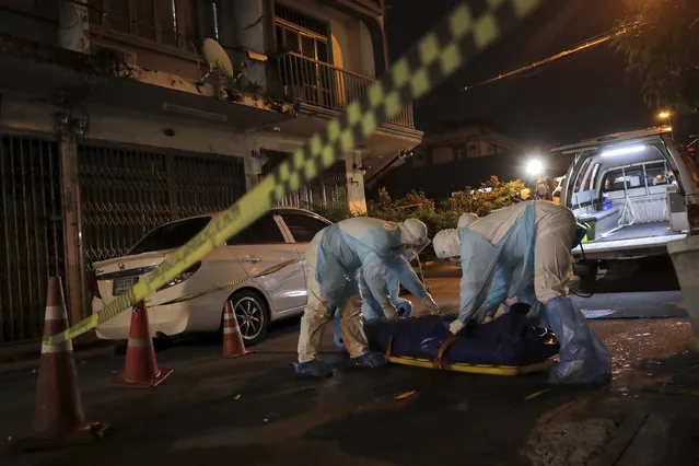 Thai volunteers with PPE protection suits collect a dead body which was left for hours on a road in Bangkok, Thailand on July 20, 2021. Thailand's already locked down capital on Friday, July 23, 2021 shut down parks and the few remaining public places available to residents, as the country registered a new record high of confirmed COVID-19 infections. The near total restriction on movements in the capital came as the prime minister demanded officials find ways to get the sick into hospitals after people were found dead on the streets of Bangkok. (Photo by Patipat Janthong/Voice via AP Photo)