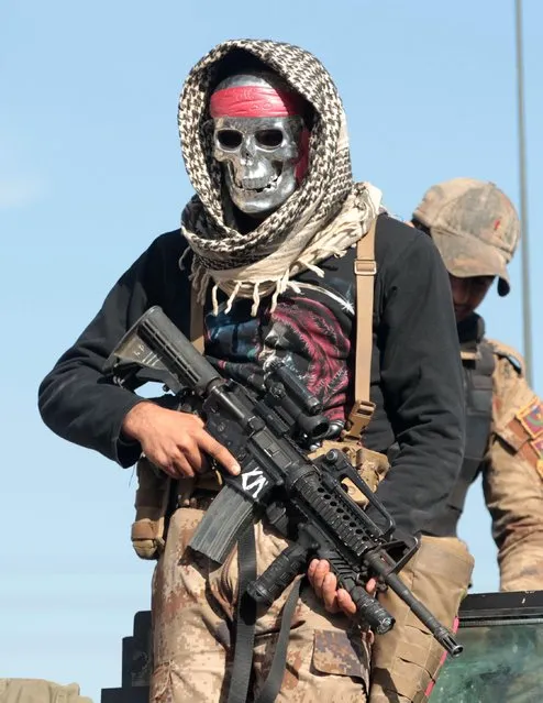 A masked Iraqi counter- terrorism service member (CTS) poses for a picture in the town of Bartalla, east of Mosul, as they search for Islamic State (IS) group fighters on January 18, 2017, during an ongoing military operation against the jihadists Iraqi forces have fully retaken east Mosul from the Islamic State group, a top commander said, three months after a huge offensive against the jihadist bastion was launched. (Photo by Ahmad Al-Rubaye/AFP Photo)