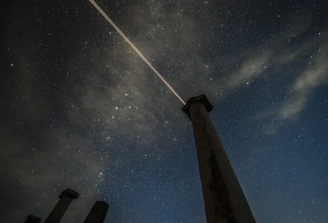 A plane streaks through the sky during the Perseid meteor shower over the archaeological site Stobi, near Negotino, Republic of North Macedonia, 12 August 2021. The Perseid meteor shower occurs every year in August when the Earth passes through debris and dust of the Swift-Tuttle comet. (Photo by Georgi Licovski/EPA/EFE)