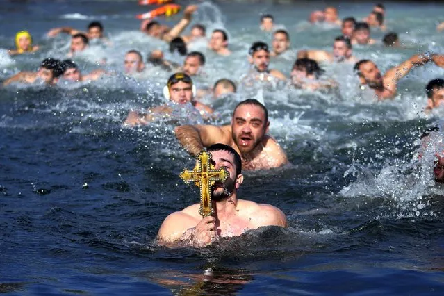 Greek Orthodox faithful holds up a wooden crucifix after retrieving it in the Golden Horn during Epiphany day in Istanbul, Turkey, Saturday, January 6, 2024. By tradition, a crucifix is cast into the waters of a lake or river, and it is believed that the person who retrieves it will be freed from evil spirits and will be healthy throughout the year. (Photo by Khalil Hamra/AP Photo)