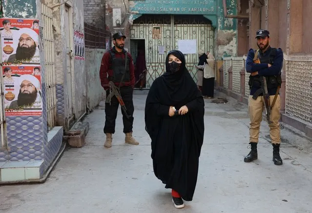 A woman arrives to cast her vote at a polling station as police officers stand guard during the general election, in Peshawar, Pakistan on February 8, 2024. (Photo by Fayaz Aziz/Reuters)