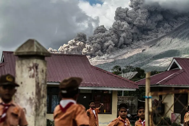 Elementary school children play outside their classrooms as mount Sinabung volcano spews thick volcanic ash in the background on February 10, 2017 in Karo, Indonesia. Mount Sinabung is one of the most active volcanoes in Indonesia and last erupted in May 2016, killing seven people. (Photo by Albert Damanik/Barcroft Images)