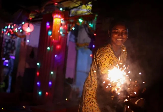 A woman and her son hold firecrackers during Diwali, the Hindu festival of lights, in Mumbai, India, November 4, 2021. (Photo by Francis Mascarenhas/Reuters)