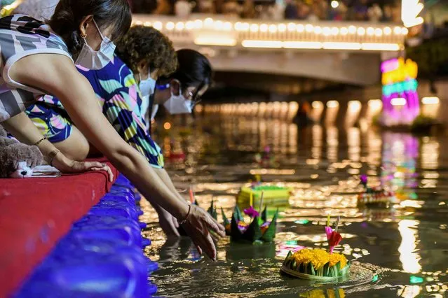 People wearing face masks to prevent the spread of the coronavirus disease (COVID-19), gather to place krathongs (floating baskets) into a river during the Loy Krathong festival, which is held as a symbolic apology to the goddess of the river in Bangkok, Thailand, November 19, 2021. (Photo by Chalinee Thirasupa/Reuters)