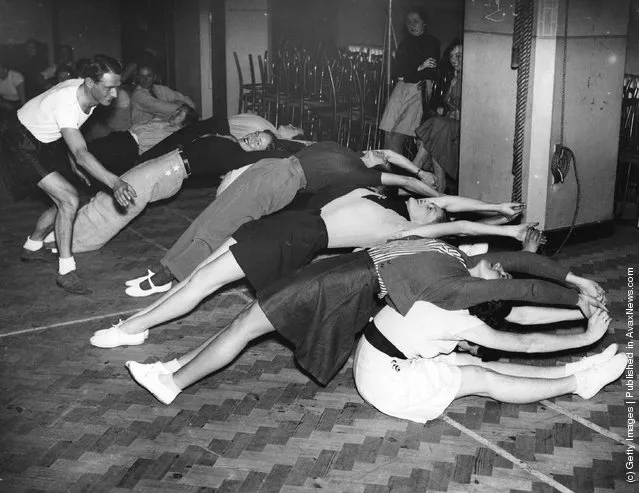 1936:  Would-be skiers taking lessons from an Austrian ski champion in the gym, learning that suppleness is essential in skiing