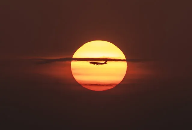 An airplane flies over Panama Bay, in Panama City during sunrise on April 8, 2019. (Photo by Luis Acosta/AFP Photo)