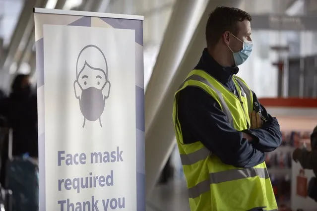A security worker and a sign to remind travellers to wear a face mask at Amsterdam Schiphol airport on December 2, 2021 in Amsterdam, Netherlands. The Netherlands and other nations worldwide temporarily banned most travellers from South Africa after a new variant of Covid-19 named Omicron was discovered. Omicron has sparked worries around the world that it could resist vaccinations and prolong the nearly two-year Covid-19 pandemic. (Photo by Pierre Crom/Getty Images)