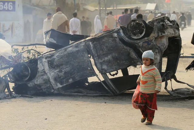 A child walks past burnt-out vehicles set on fire by a mob after allegations of desecration of the holy Koran by a suspect, in Charsadda, Pakistan, 29 November 2021. A mob attacked and set on fire a police station in Charsadda on 28 November demanding that authorities hand over a man arrested for allegedly desecrating the Holy Koran. (Photo by Bilawal Arbab/EPA/EFE)