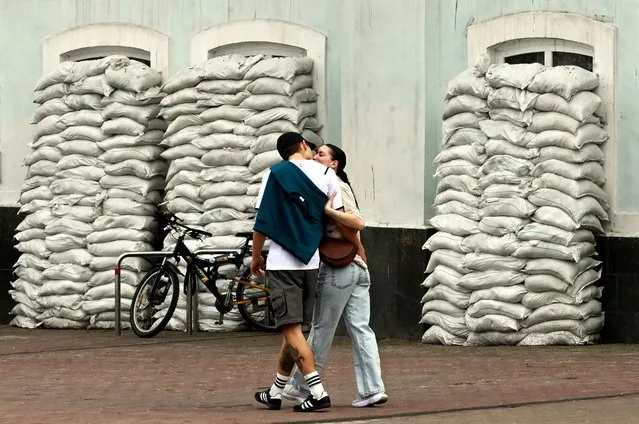 A couple kisses while walking by sandbags protecting the windows of the “Palace of Children's Creativity” in Kyiv on April 1, 2024, amid Russian invasion of Ukraine. (Photo by Sergei Supinsky/AFP Photo)