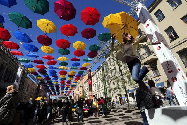 People visit an art installation “Alley of Flying Umbrellas” in central St. Petersburg, Russia, May 15, 2015. Art installation inspired by “Umbrella Sky Project” of Portuguese town of Agueda and was made of 500 colored umbrellas. (Photo by Anatoly Maltsev/EPA)
