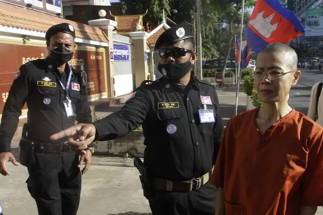 Court securities direct Cambodian-American lawyer Theary Seng, right, dressed in a prison-style orange outfit, to the entrance of Phnom Penh Municipal Court in Phnom Penh, Cambodia, Tuesday, January 4, 2022. Cambodian security forces on Tuesday briefly detained Theary, a prominent rights activist, as she walked barefoot near the prime minister’s residence in Phnom Penh, wearing the orange outfit and Khmer Rouge-era ankle shackles. She was released, shortly afterwards, and arrived at the Phnom Penh court for the resumption of her trial on treason charges. (Photo by Heng Sinith/AP Photo)