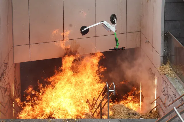 An electric scooter is thrown into the fire during a protest by Belgian farmers over price pressures, taxes and green regulation, on the day of an EU agriculture ministers' meeting in Brussels, Belgium, on March 26, 2024. (Photo by Yves Herman/Reuters)