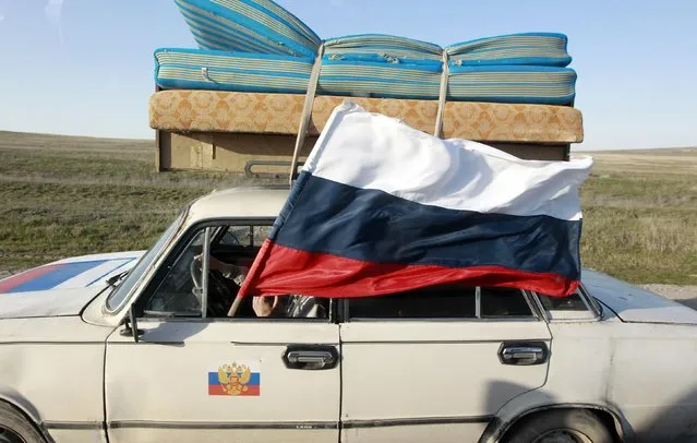 A car drives with a Russian flag on a road outside the Crimean port city of Feodosia March 24, 2014. Ukraine announced the evacuation of its troops and their families from Crimea on Monday, effectively acknowledging defeat in the face of Russian forces, who stormed one of the last remaining Ukrainian bases on the peninsula. (Photo by Shamil Zhumatov/Reuters)